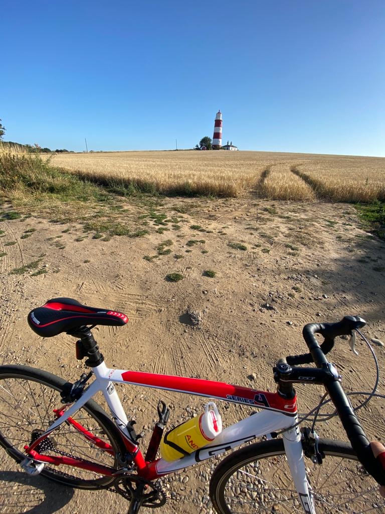 A picture of a bike with a straw field and a lighthouse in the background