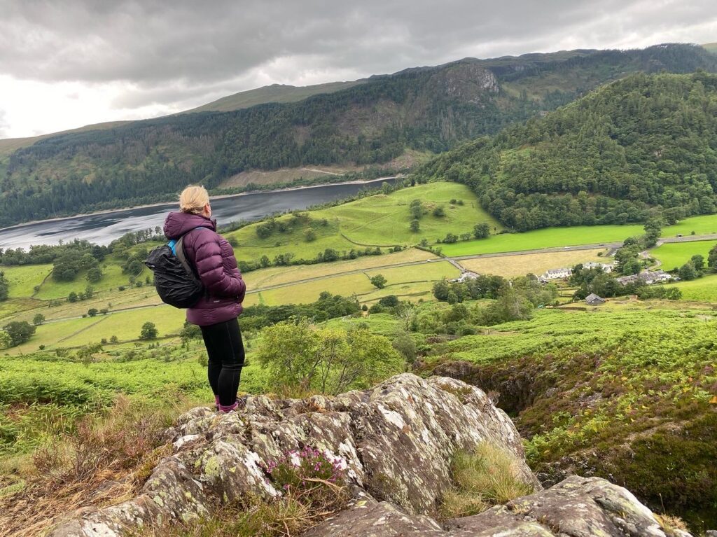 Kerry standing on a rock looking at mountain scenery with Thirlmere resevoir at the base
