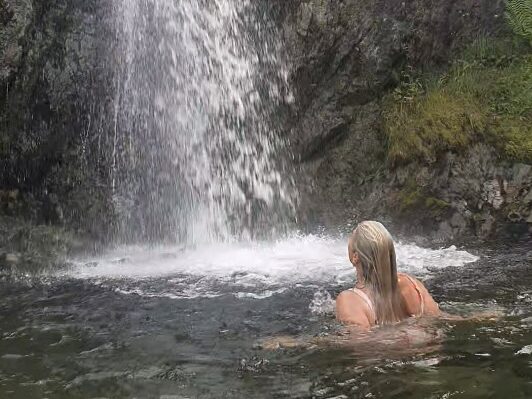 Kerry at the base of a waterfall, looking up at the water cascading done the rocks